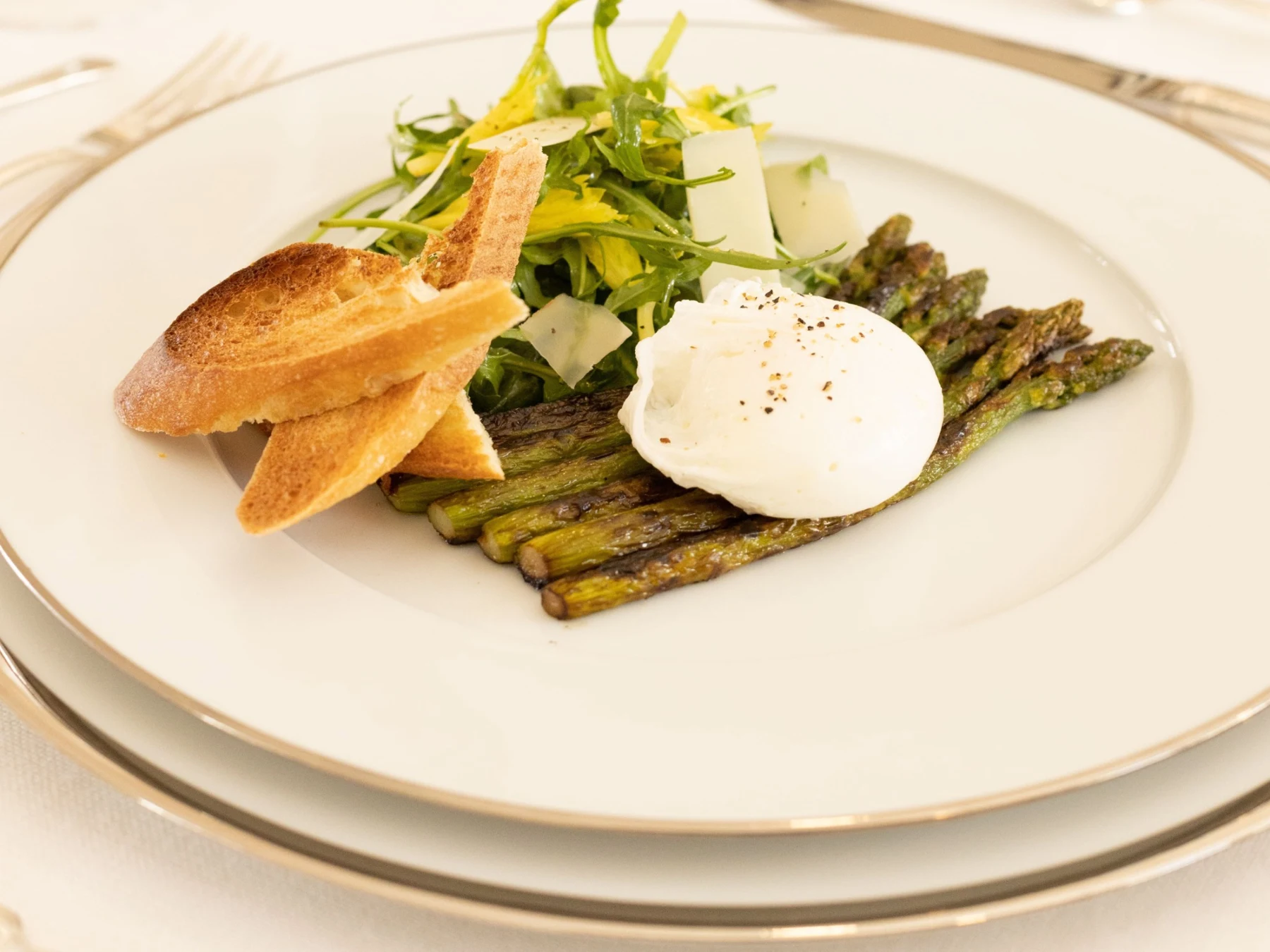 Une assiette avec un œuf, des asperges, des verdures et du pain grillé